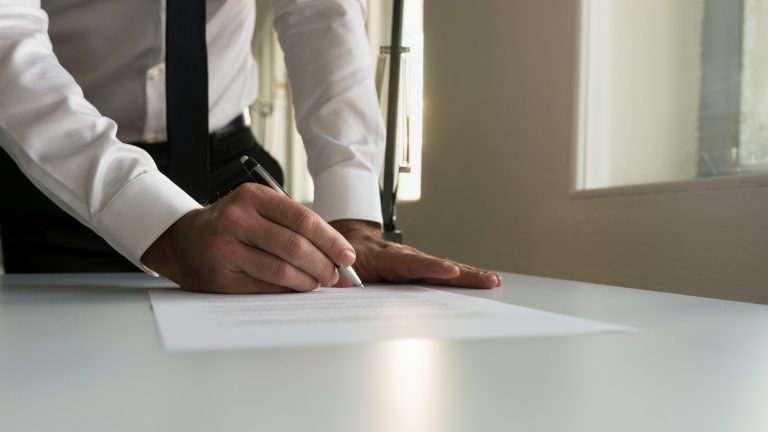 Businessman in office signing contract, document or legal papers