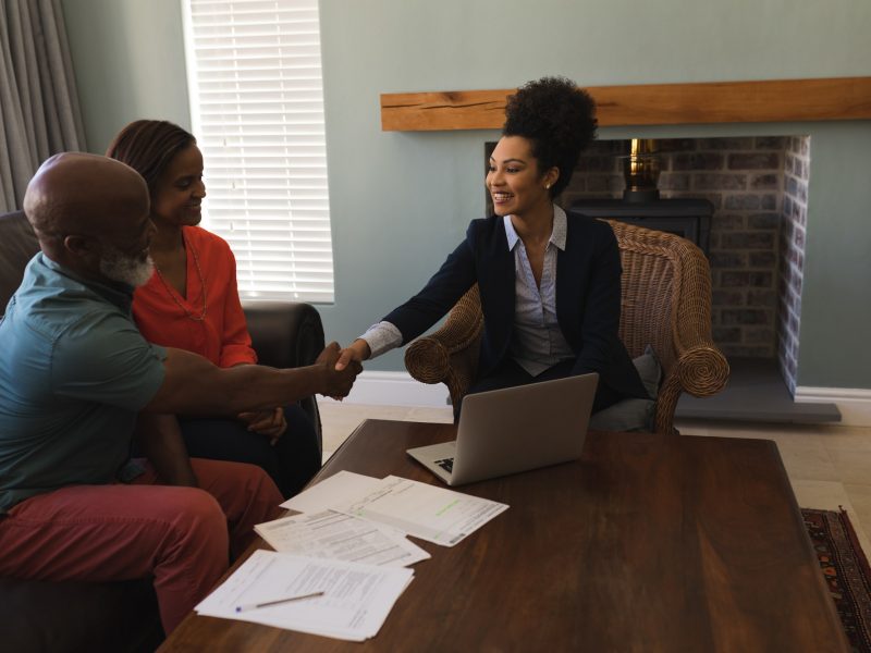 Female real estate agent shaking hands with a senior man in the living room at home