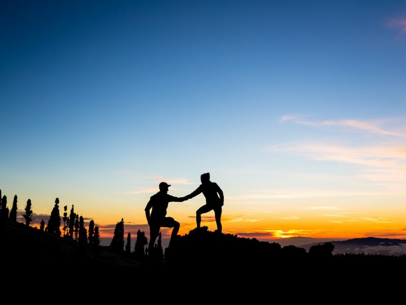 Teamwork couple climbing with helping hand